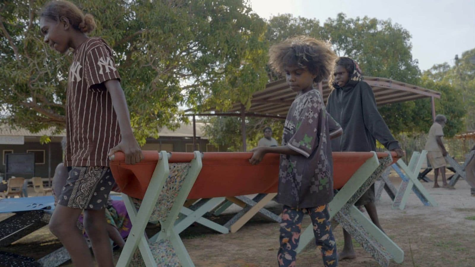 Two young people carrying an orange Stretch Bed at Gamardi