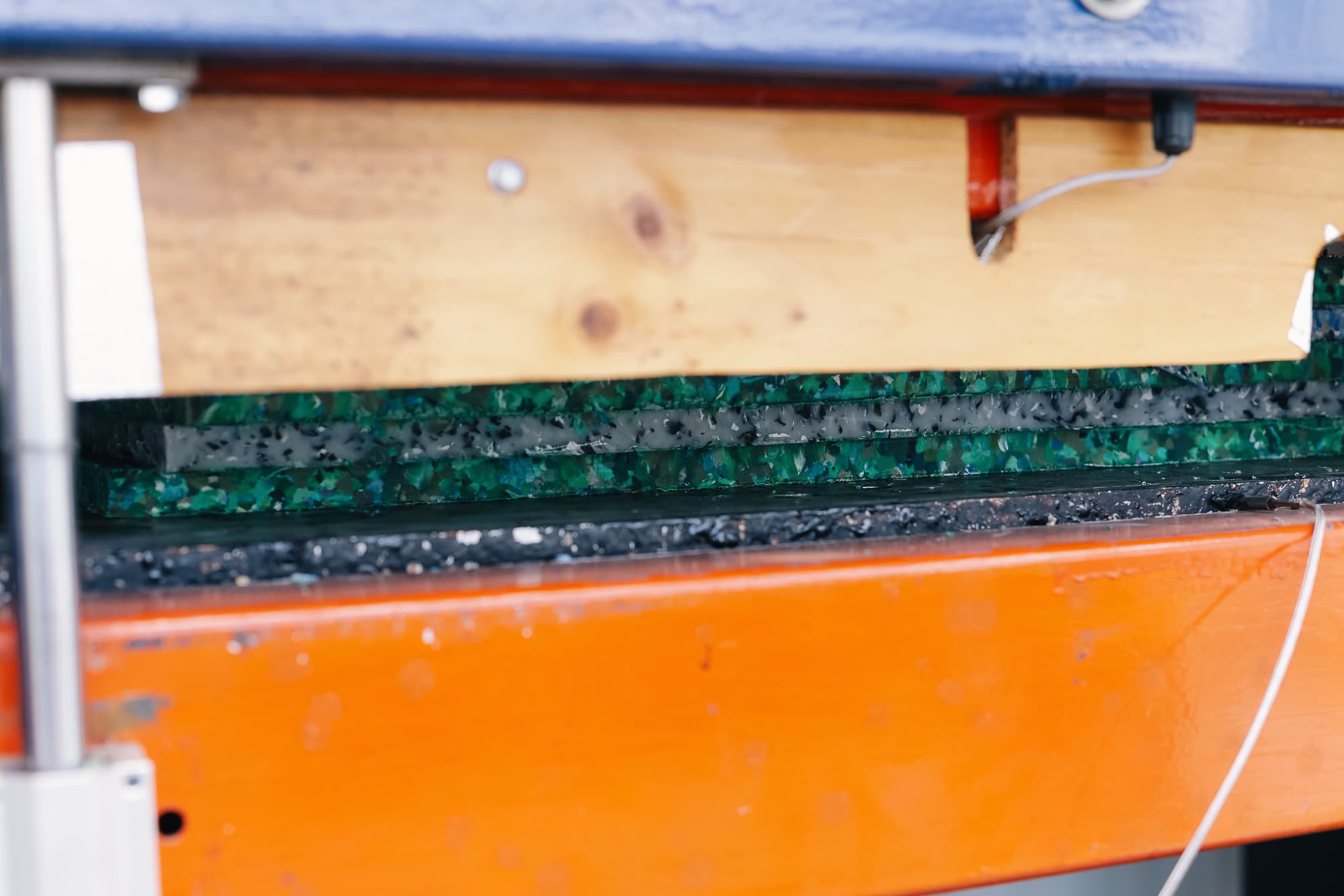 Hydraulic press compressing recycled plastic into sheets