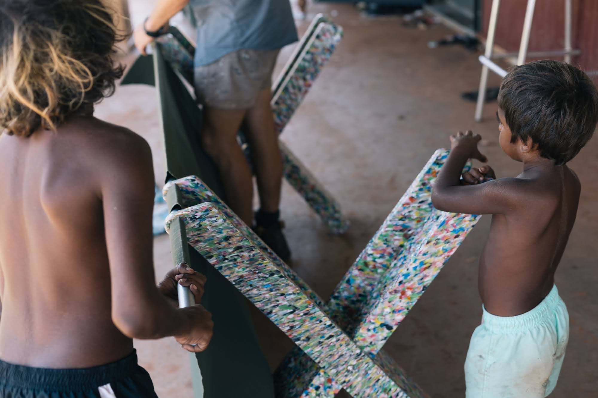 Kids in community clipping recycled plastic legs onto steel poles
